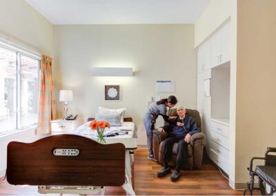 Nurse checking up senior's heartbeat while sitting on the lazy sofa chair